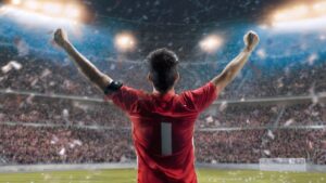 Soccer player celebrating after scoring a goal worth one point in packed stadium