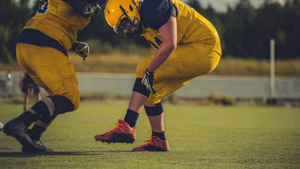 High school lineman wearing proper football cleats blocking opponent safely